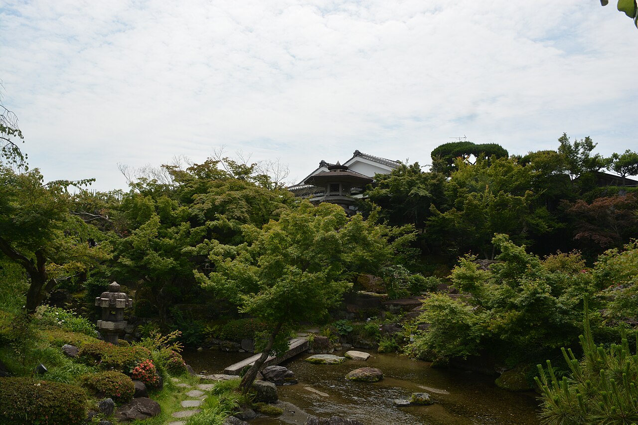 Stone lantern, pond and green trees in the garden of Ganko Takasegawa Nijoen